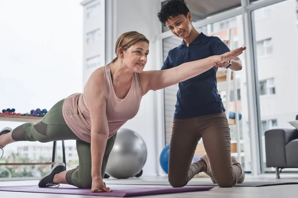 Coach sportif accompagnant une femme pendant une séance à domicile